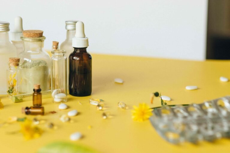 Various glass bottles, capsules, tablets, and a dropper bottle are arranged on a yellow surface with scattered yellow flowers and leaves—illustrating the natural approach of How Functional Medicine Works in Las Vegas.